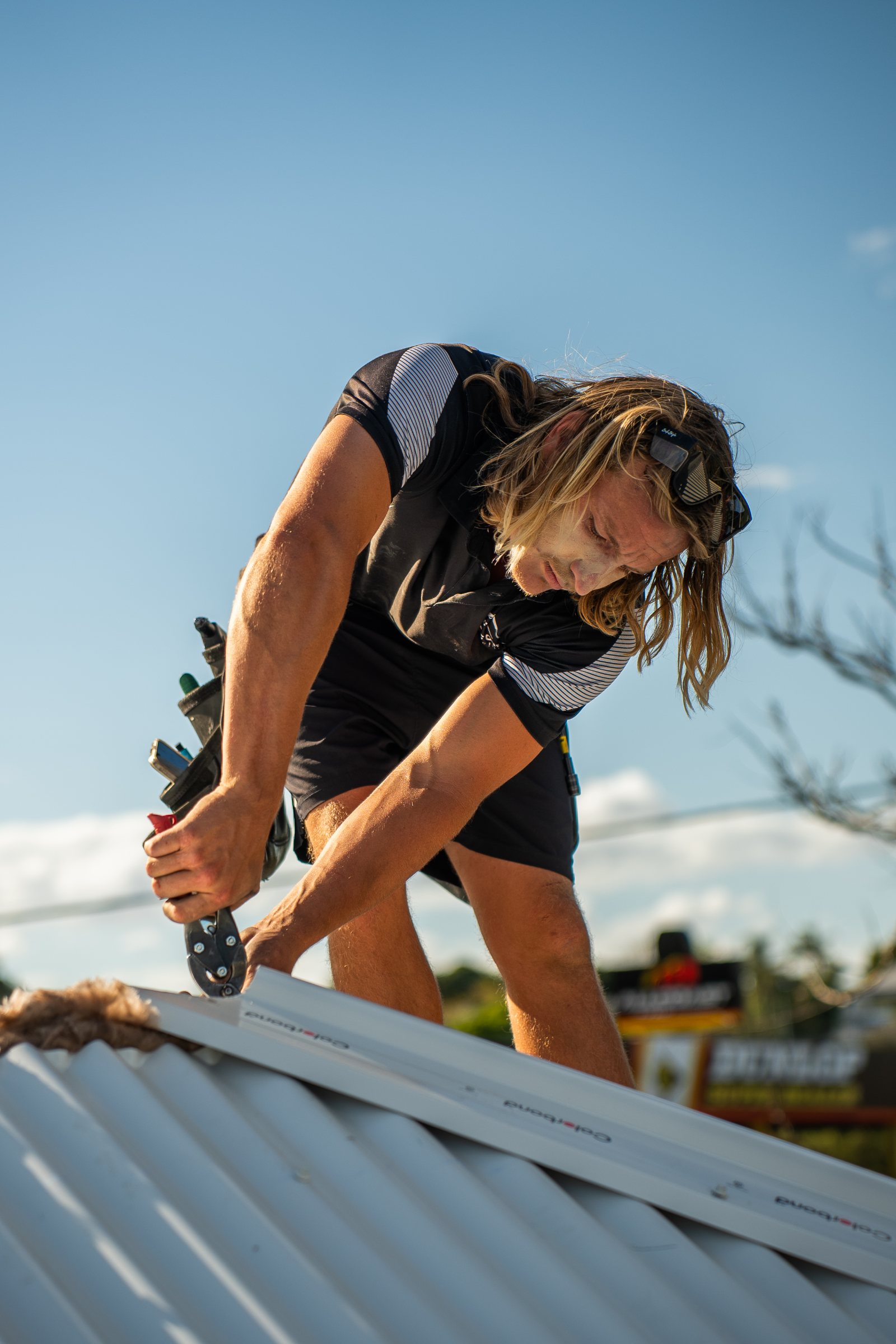 Roofer fixing metal roof sheets on a Sunshine Coast home