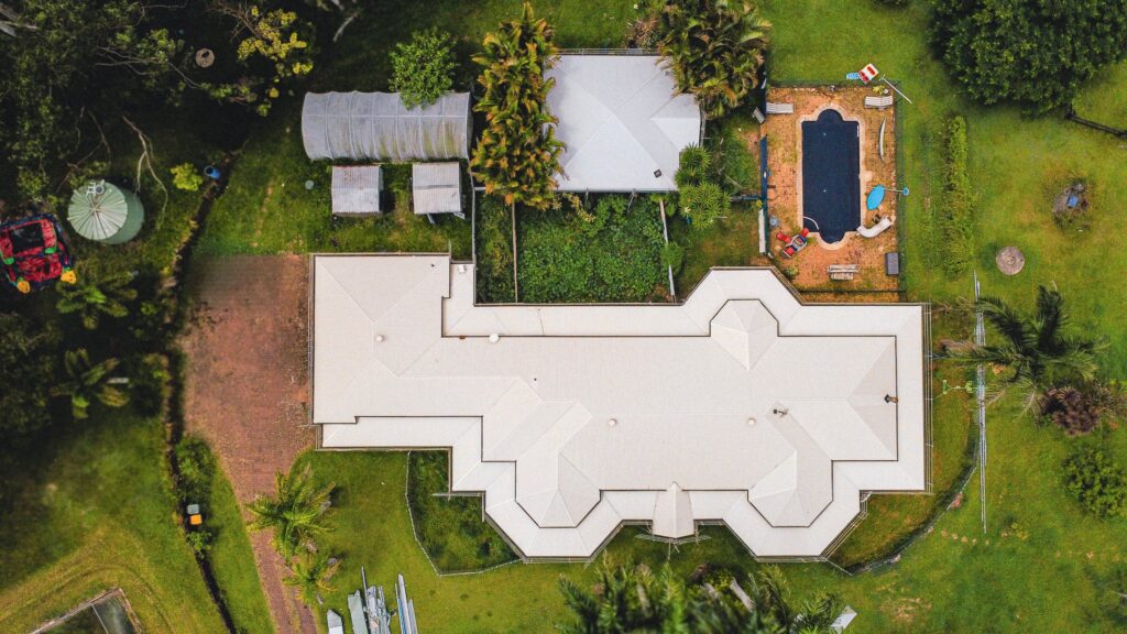 Aerial view of a light coloured metal roof on a Sunshine Coast home with pool